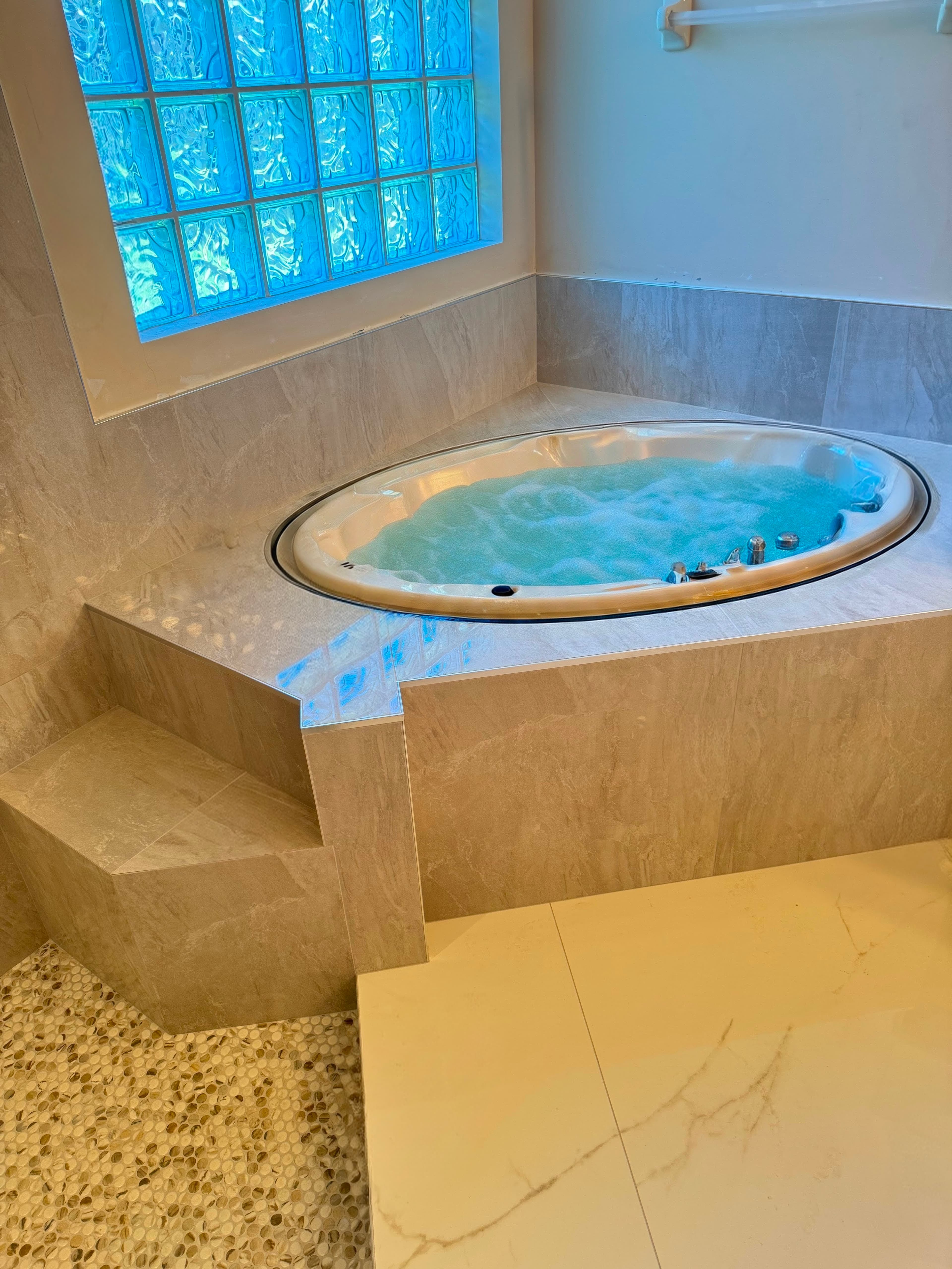 Bathroom whirlpool tub with a tiled surround and pebble mosaic floor