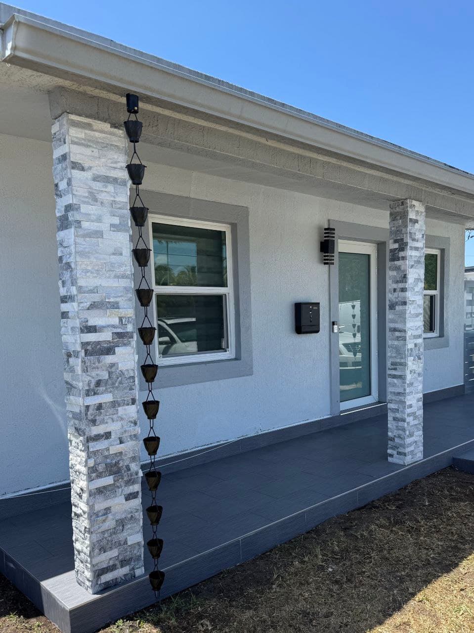 Covered front porch with stone-veneer columns and dark tile flooring